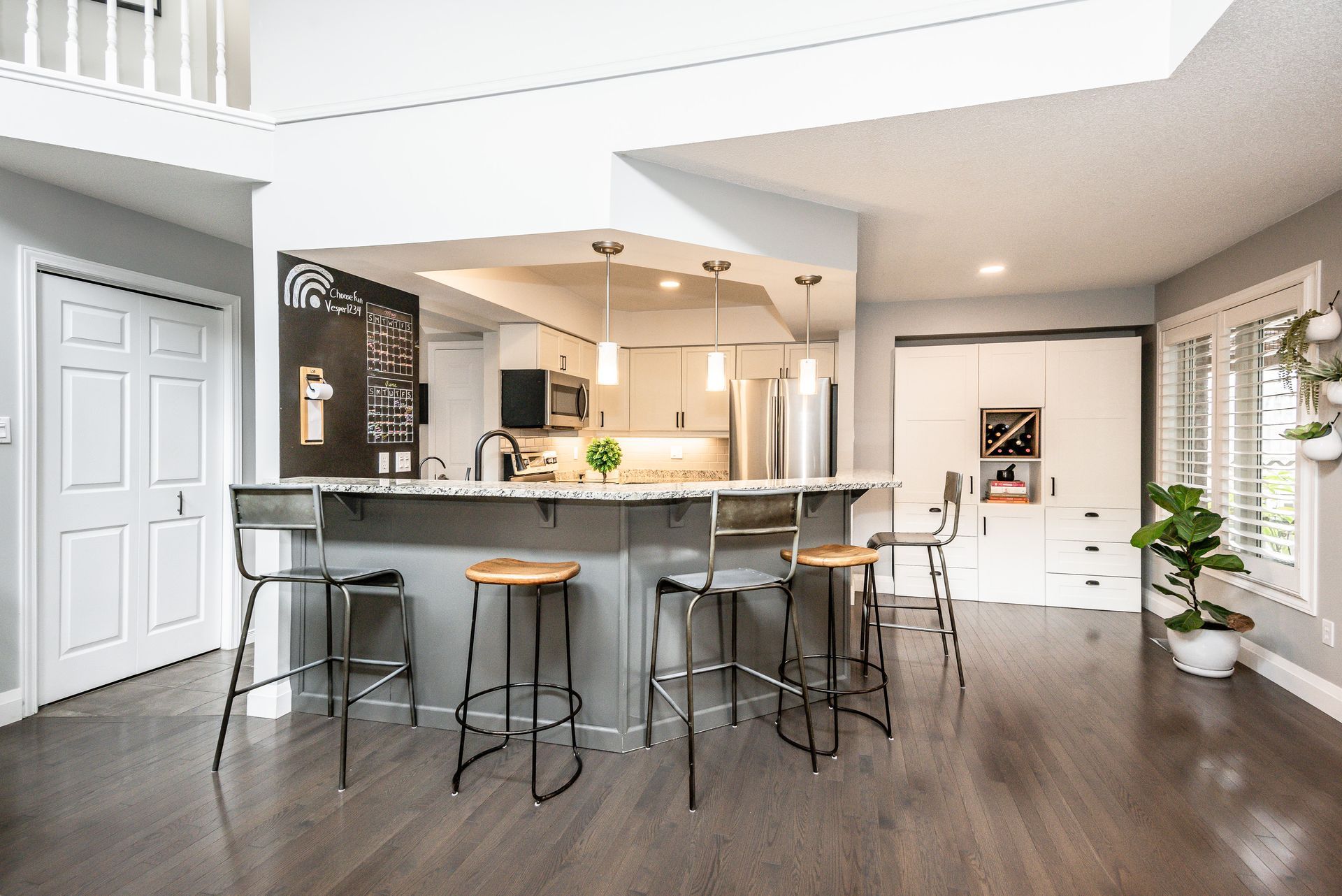 Open-concept kitchen and living area with dark wood floors, island stools, and bright natural light
