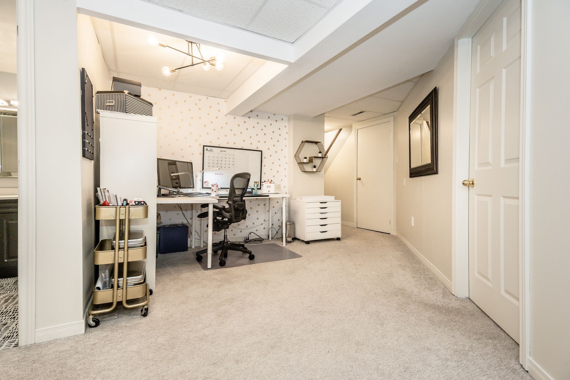 Home office in a finished basement with desk, chair, filing cabinet, and beige carpet.