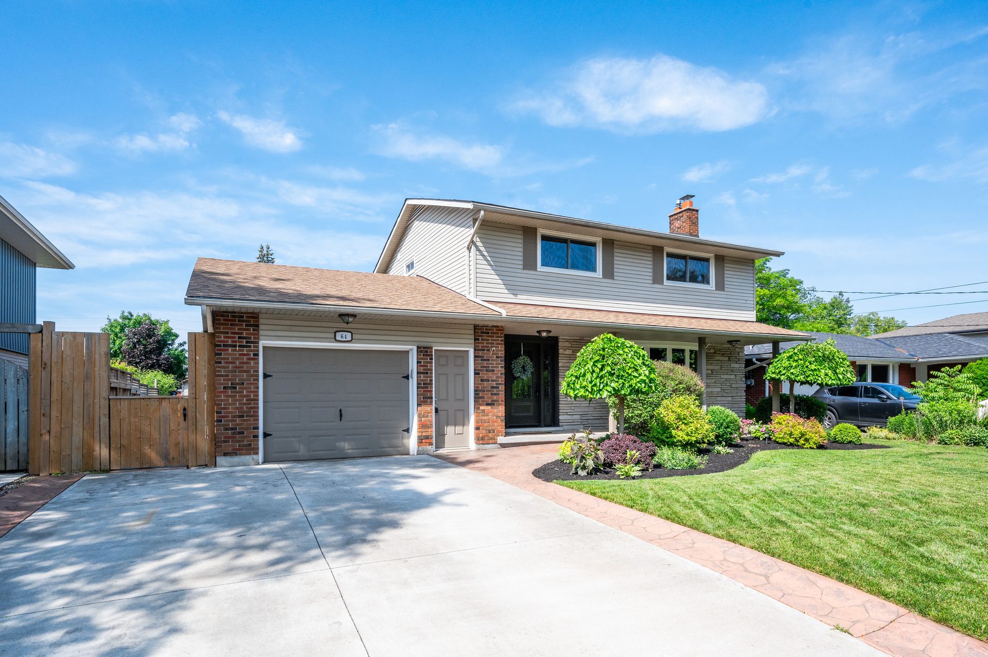 Two-story suburban house with garage, driveway, and front lawn under a clear blue sky