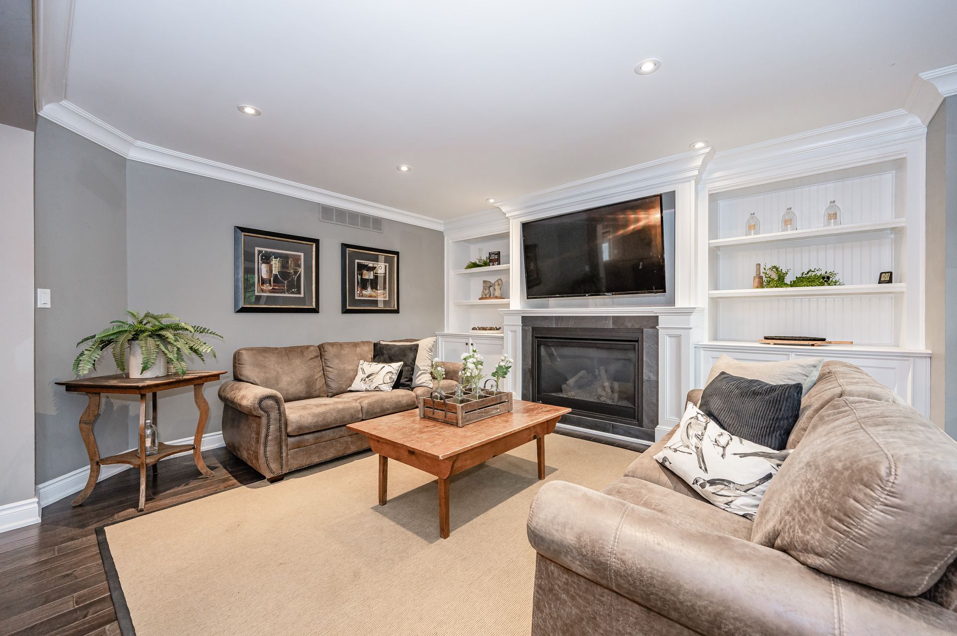 Bright living room with gray walls, beige sofas, a fireplace, TV, and wooden coffee table