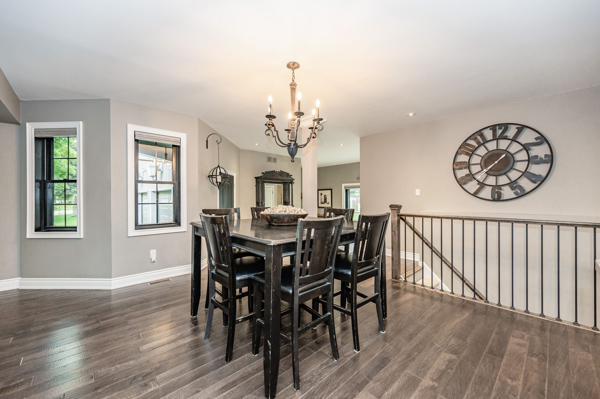 Open dining area with dark wood table, chandelier, wall clock, and hardwood floors.