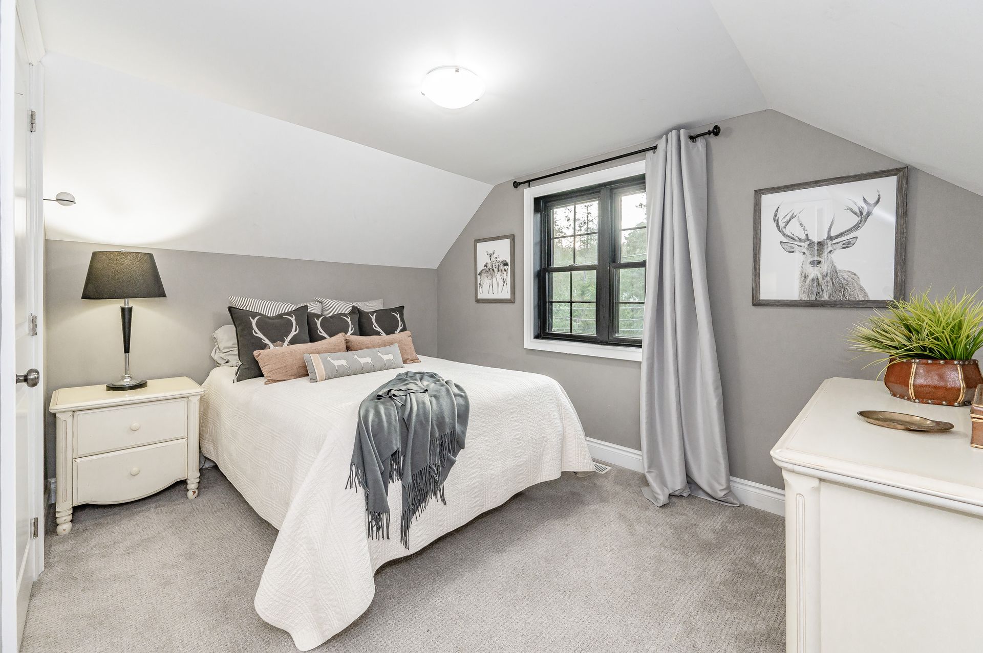 Bright gray bedroom with a white bed, nightstands, dresser, and window with curtains