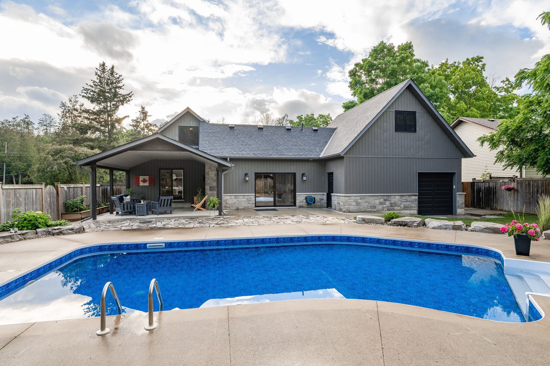 Backyard house with covered patio and blue swimming pool in the foreground