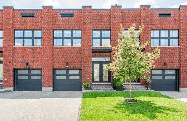 Row of modern brick townhouses with black garage doors and a green front lawn