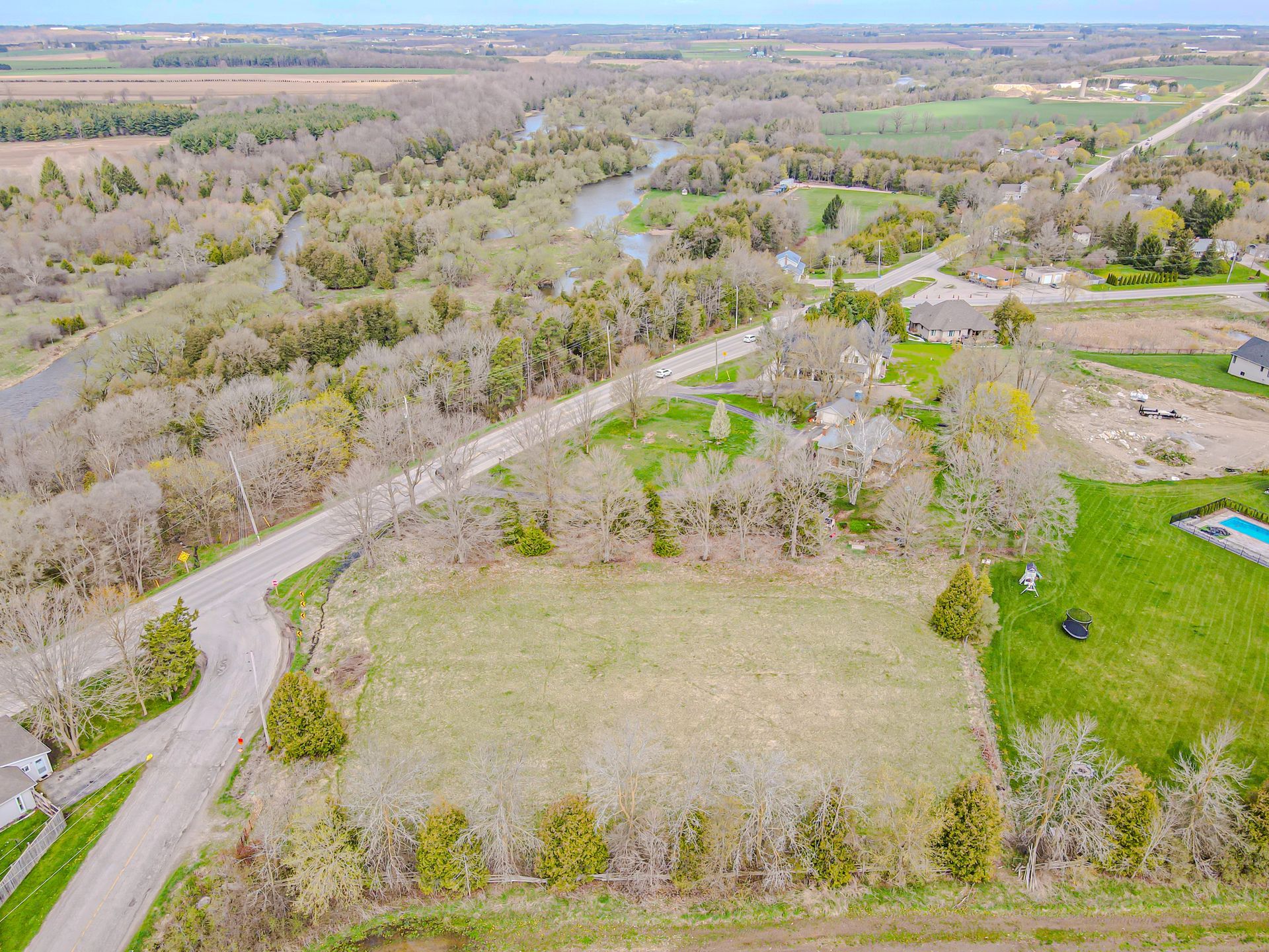 Aerial view of a rural landscape with winding roads, leafless trees, and open fields.