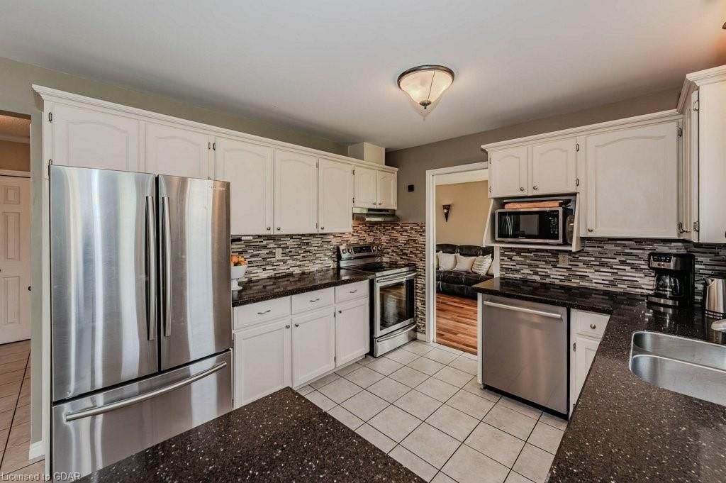 Bright kitchen with stainless steel appliances, white cabinets, and black granite countertops