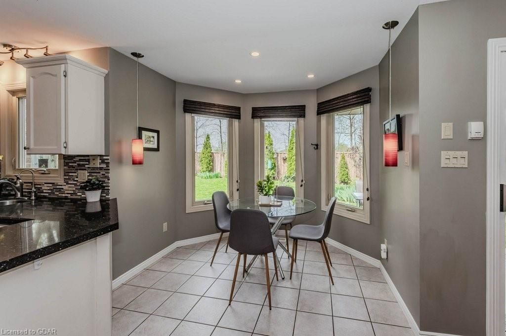 Modern kitchen with gray walls, white tile floor, and a small dining table by bright windows.
