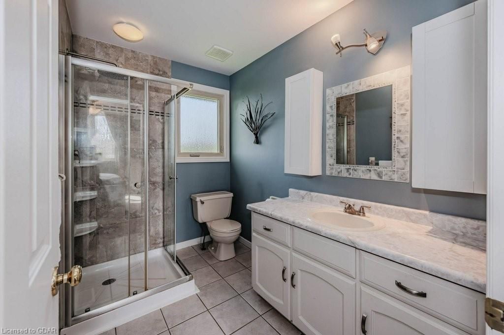 Bright bathroom with shower, toilet, and white vanity against light blue walls