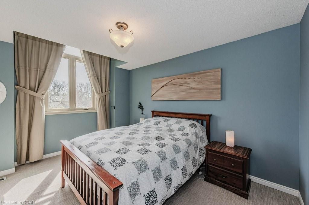 Bedroom with blue walls, a wooden bed, bedside table, window with curtains, and a ceiling light.