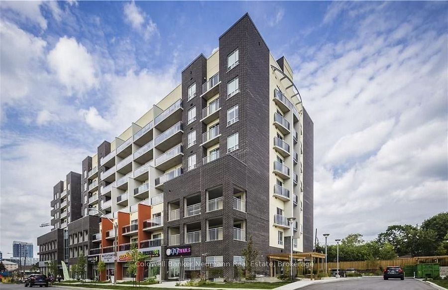 Modern apartment building with balconies and storefronts on a cloudy street corner