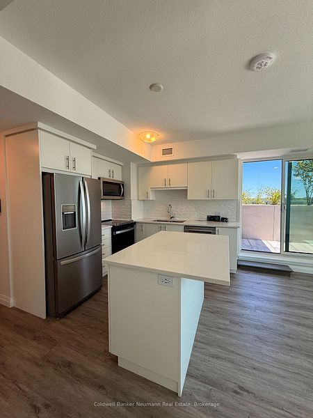 Modern empty kitchen with stainless steel appliances, white cabinets, island, and sliding glass door to patio.