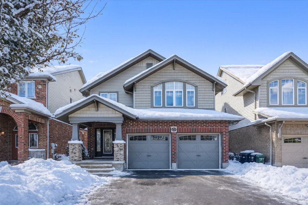 Snow-covered suburban house with a two-car garage and light winter snowfall on the roof