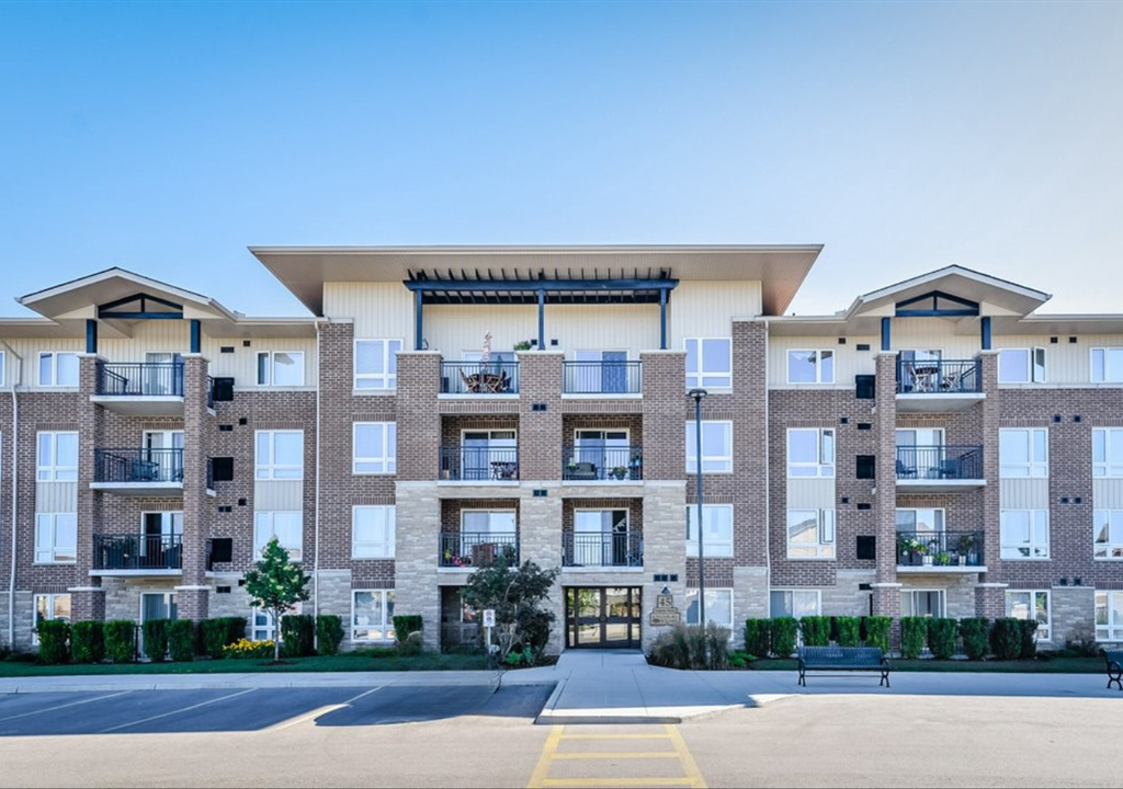 Modern apartment building exterior with balconies and a central entrance under a clear blue sky