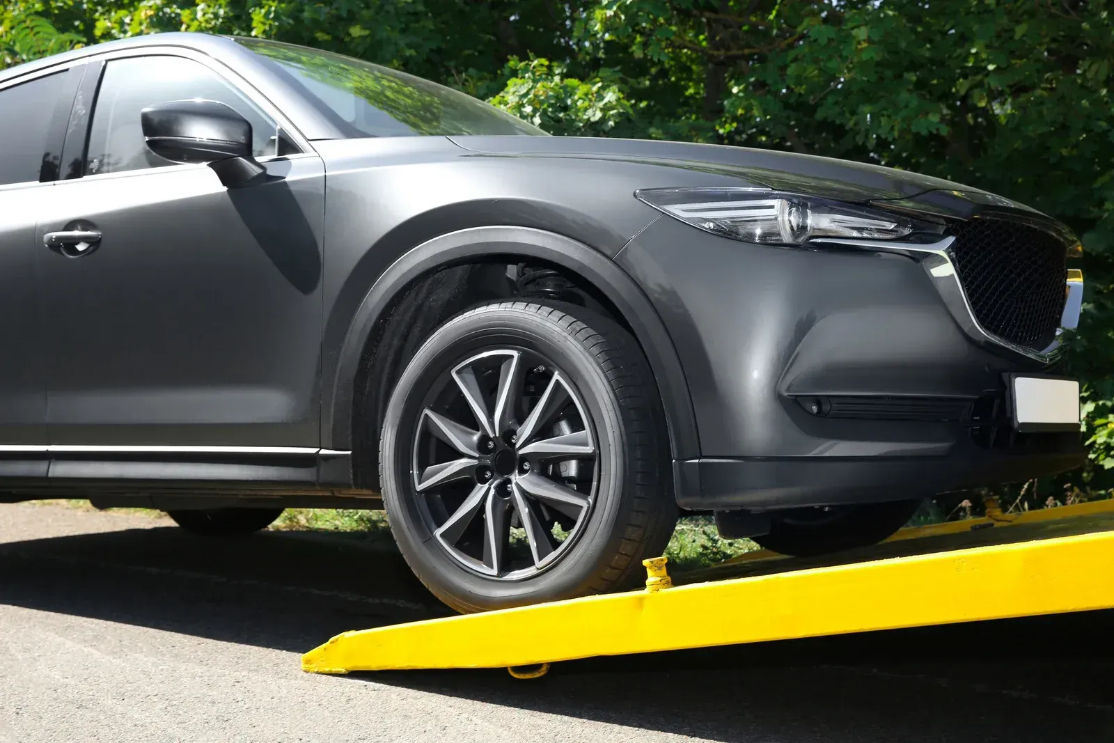 Dark gray SUV being loaded onto a yellow tow truck bed on a paved road.