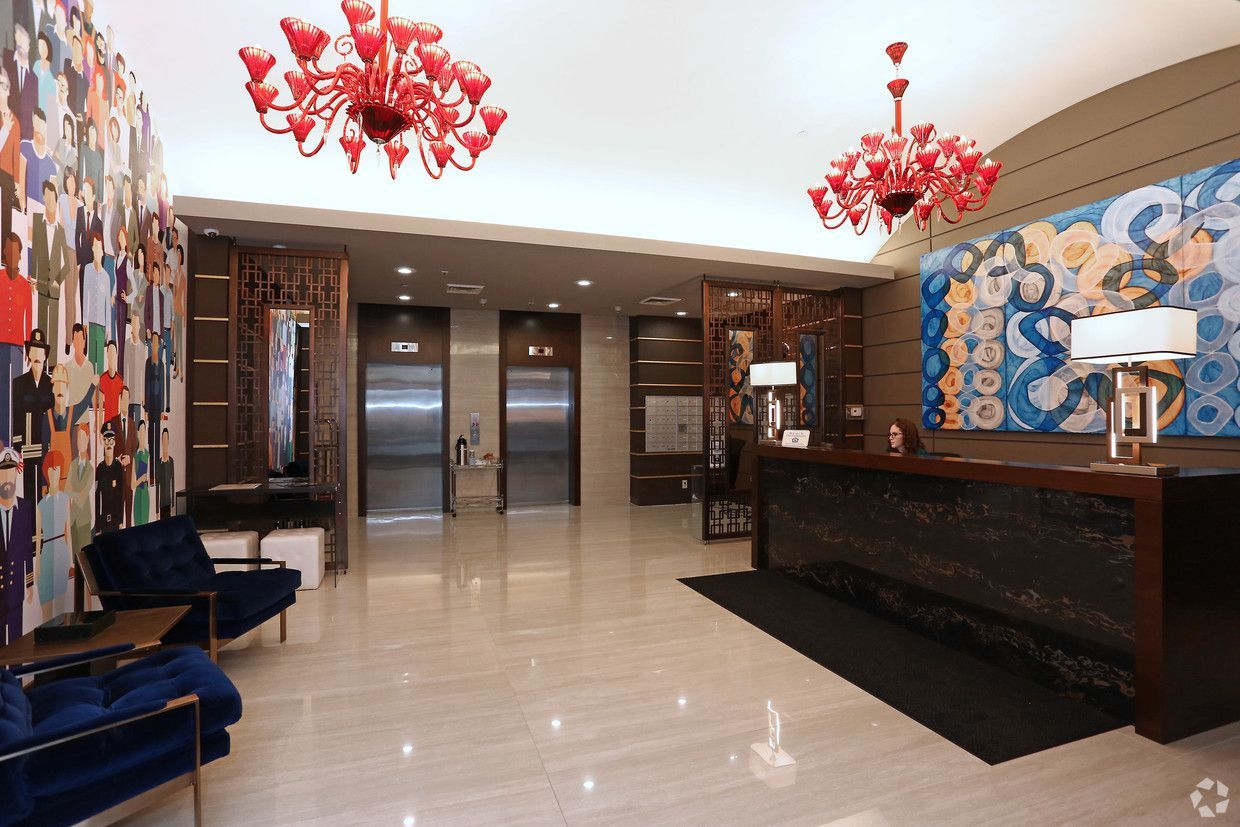 A hotel lobby with a painting on the wall and a red chandelier hanging from the ceiling.