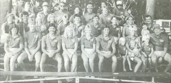 A black and white photo of a group of people sitting on a bench.