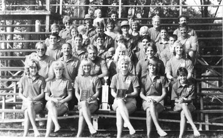 A black and white photo of a group of people sitting on bleachers