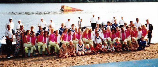 A large group of people are posing for a picture on the beach of the ski site