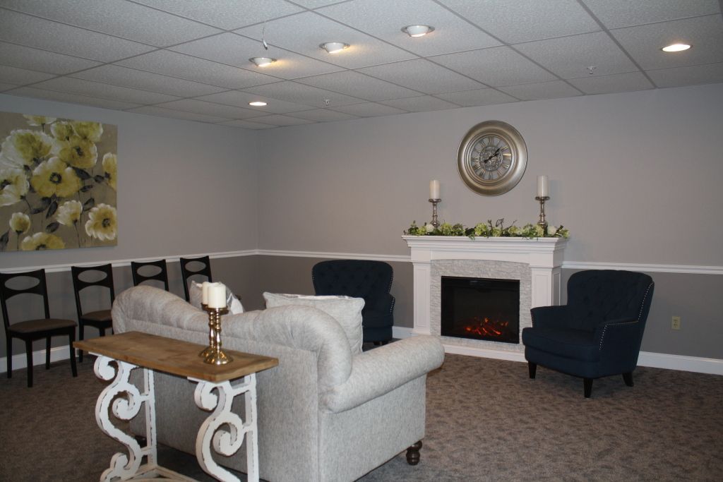 Modern living room with white sofa, dark chairs, fireplace, and decorative wall art