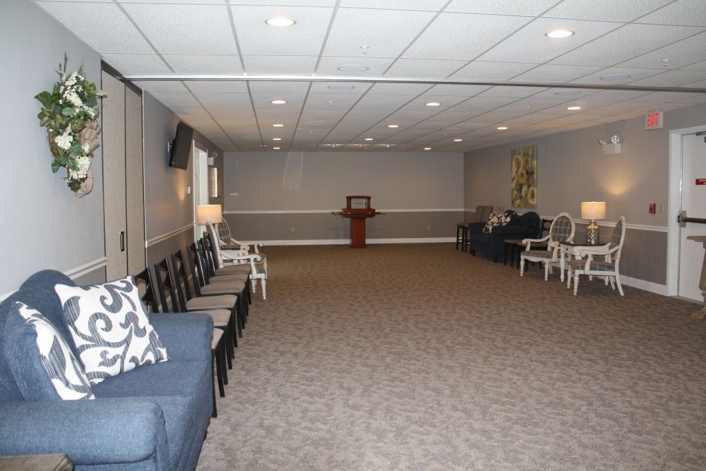 Empty banquet hall with rows of chairs, carpeted floor, and a small podium at the far end