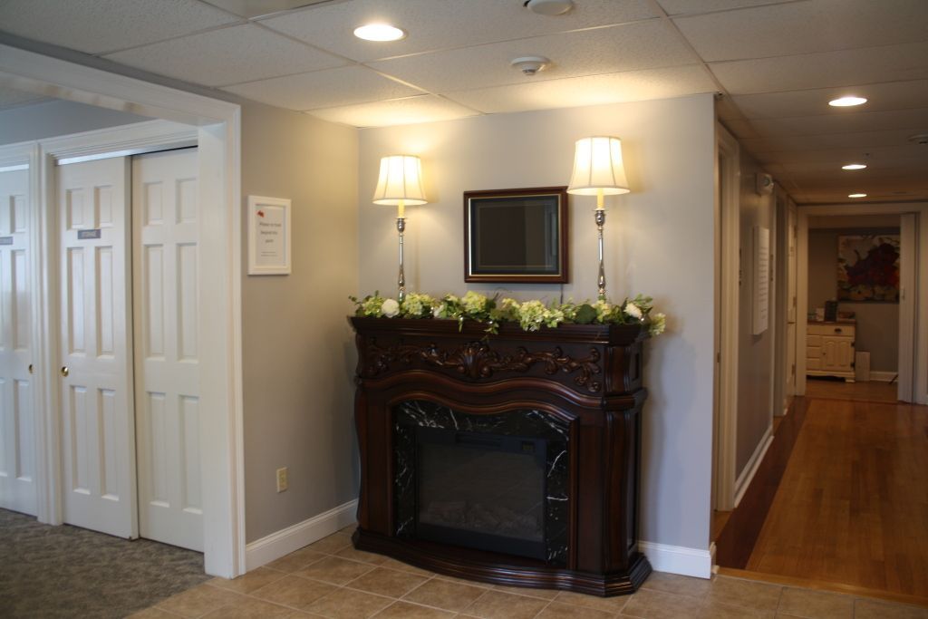 Hallway with white doors, a dark ornate fireplace, and hardwood floors in a well-lit interior.