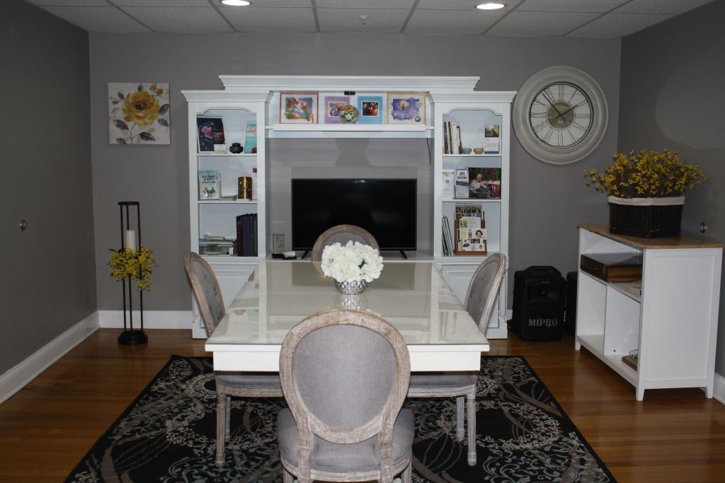 Bright dining room with a white table, upholstered chairs, fireplace, wall decor, and gray walls.