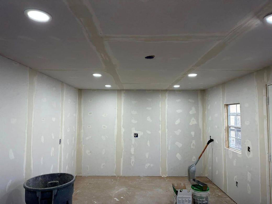 A room with drywall walls and a vacuum cleaner in it.