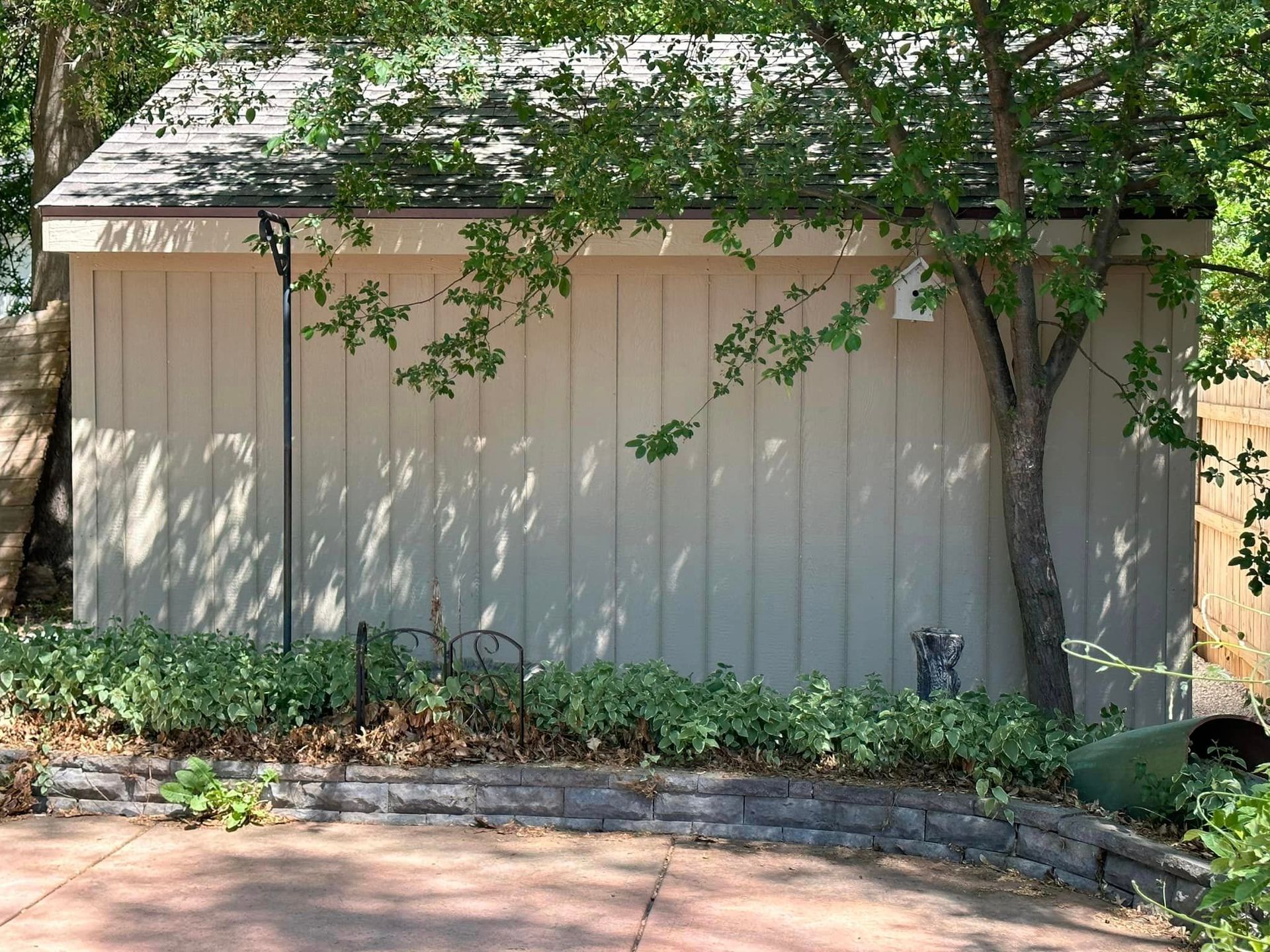 A shed with a roof and a tree in front of it