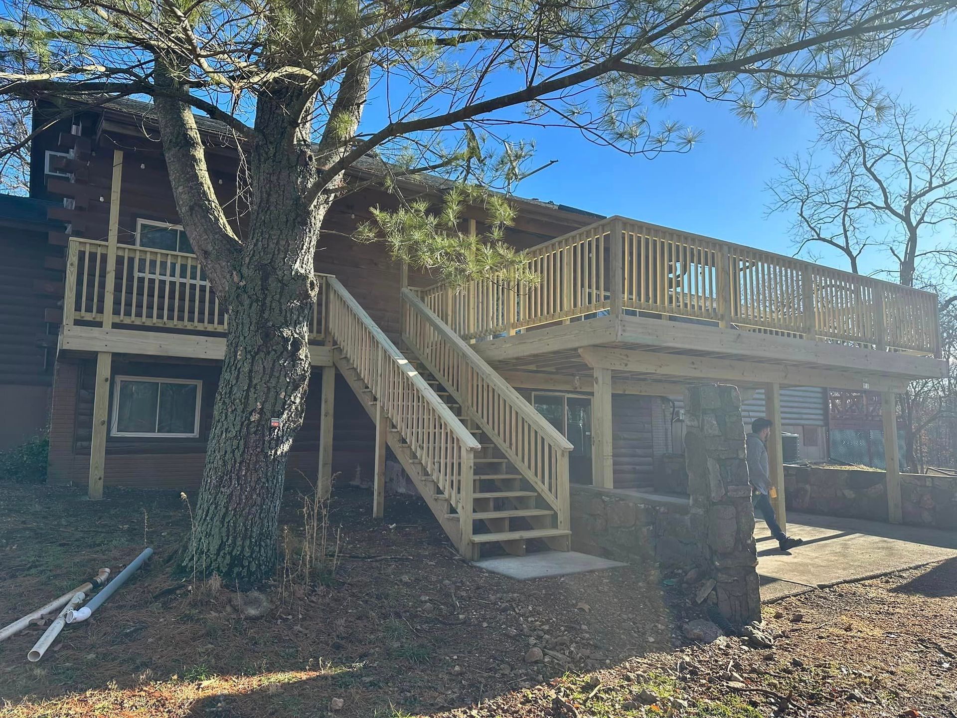 A wooden deck with stairs leading up to it is in front of a house.