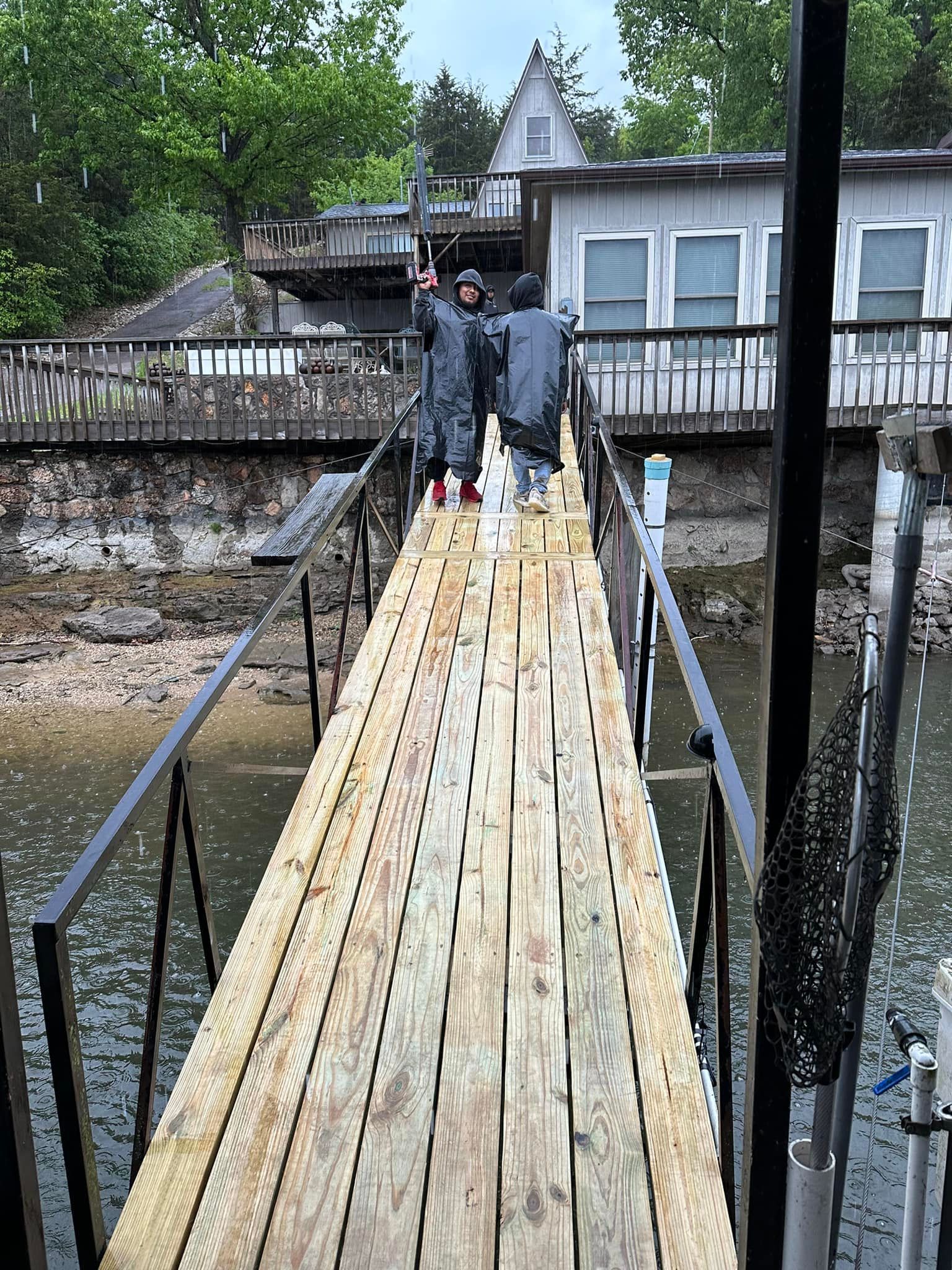 A group of people are standing on a wooden bridge over a body of water.