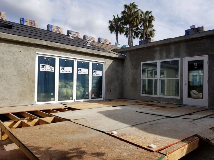 Backyard patio under construction with exposed wooden framing, concrete slabs, and stucco house walls.