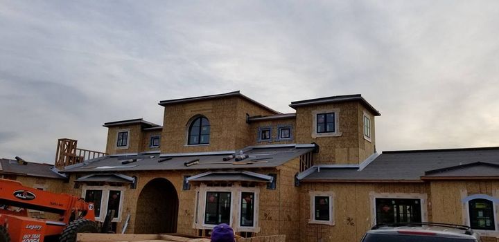 New tan brick building under construction with arched entry and exposed framing