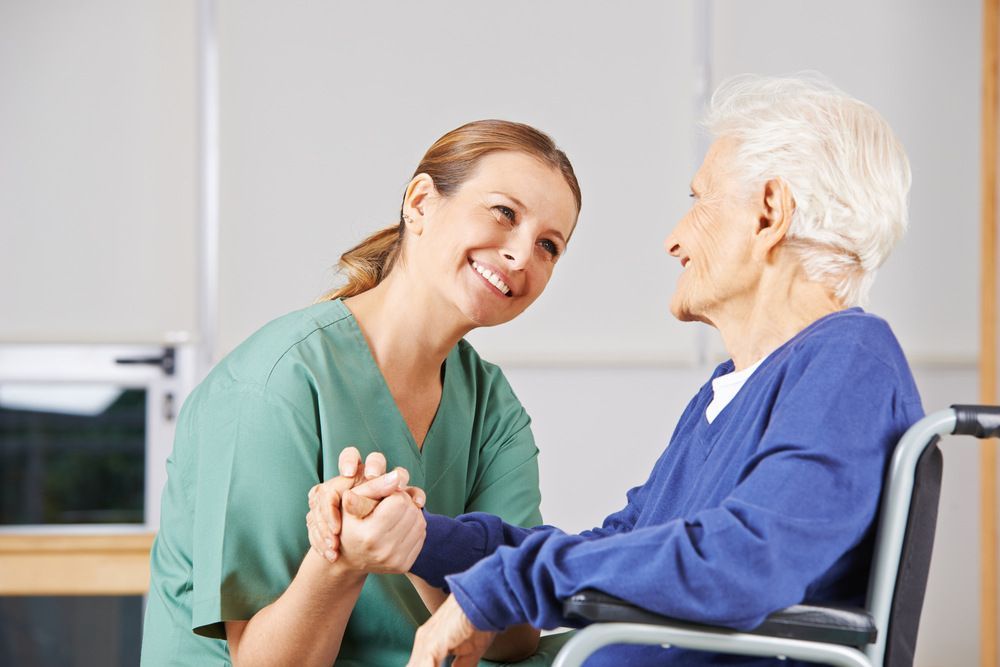 Nurse is Holding the Hand of an Elderly Woman in a Wheelchair — Universal Nurse in Blackbutt North, QLD