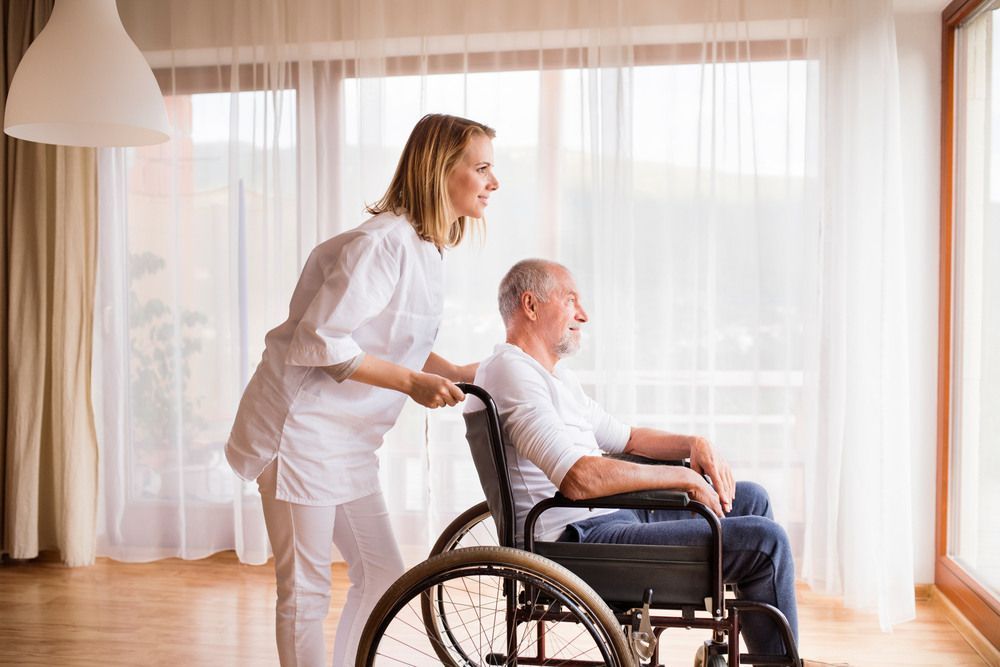 Woman Assists an Elderly Man in a Wheelchair — Universal Nurse in Nanango, QLD