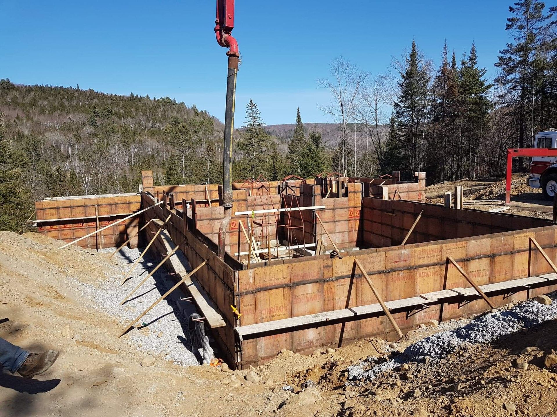 Du béton est coulé dans des coffrages en bois pour construire des fondations à flanc de colline.