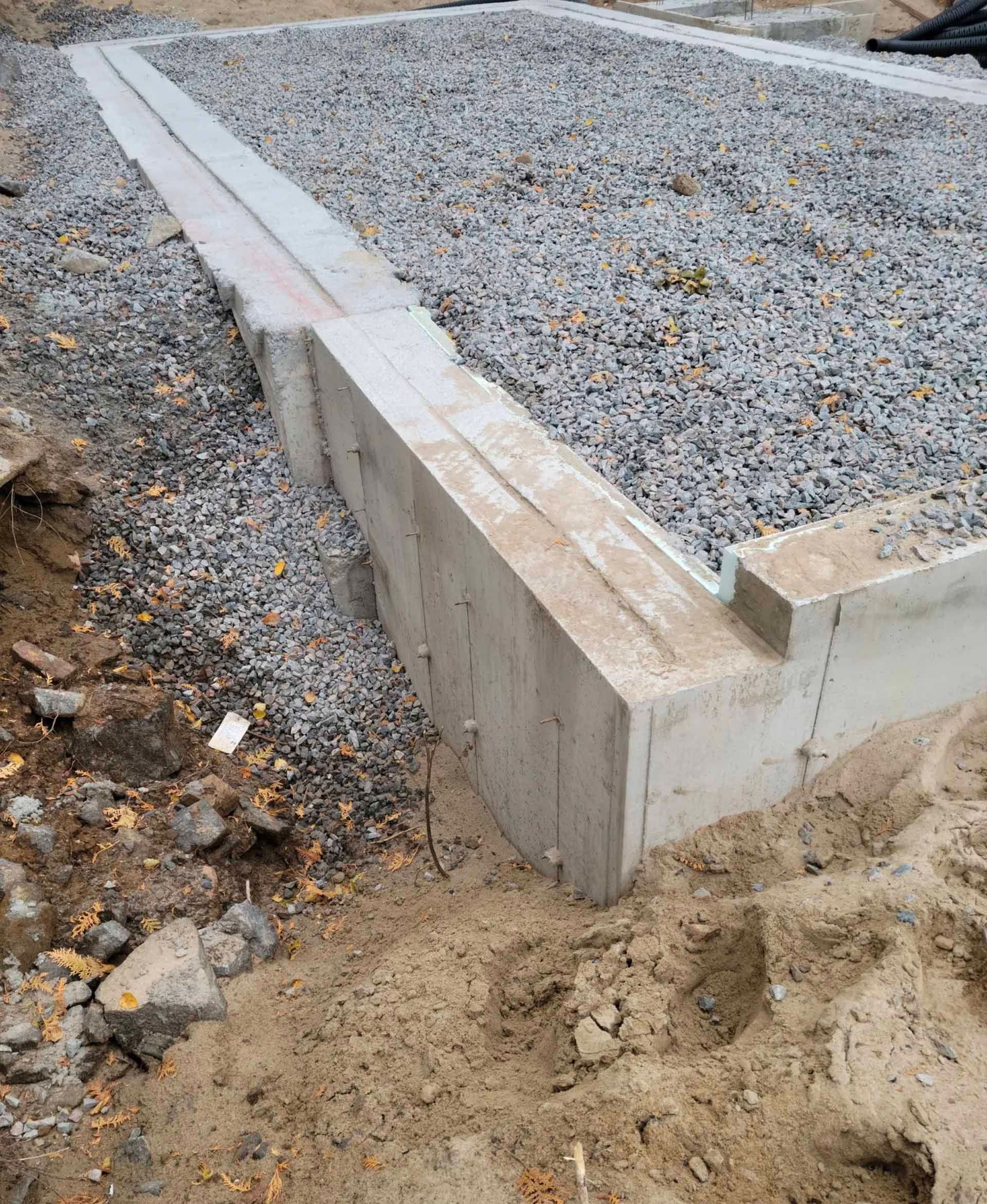 Fondations en béton avec remplissage de gravier, partiellement enterrées.
