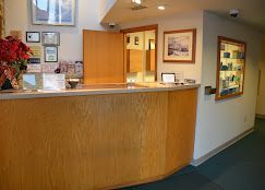 A reception desk in a dental office with a vase of flowers on it.