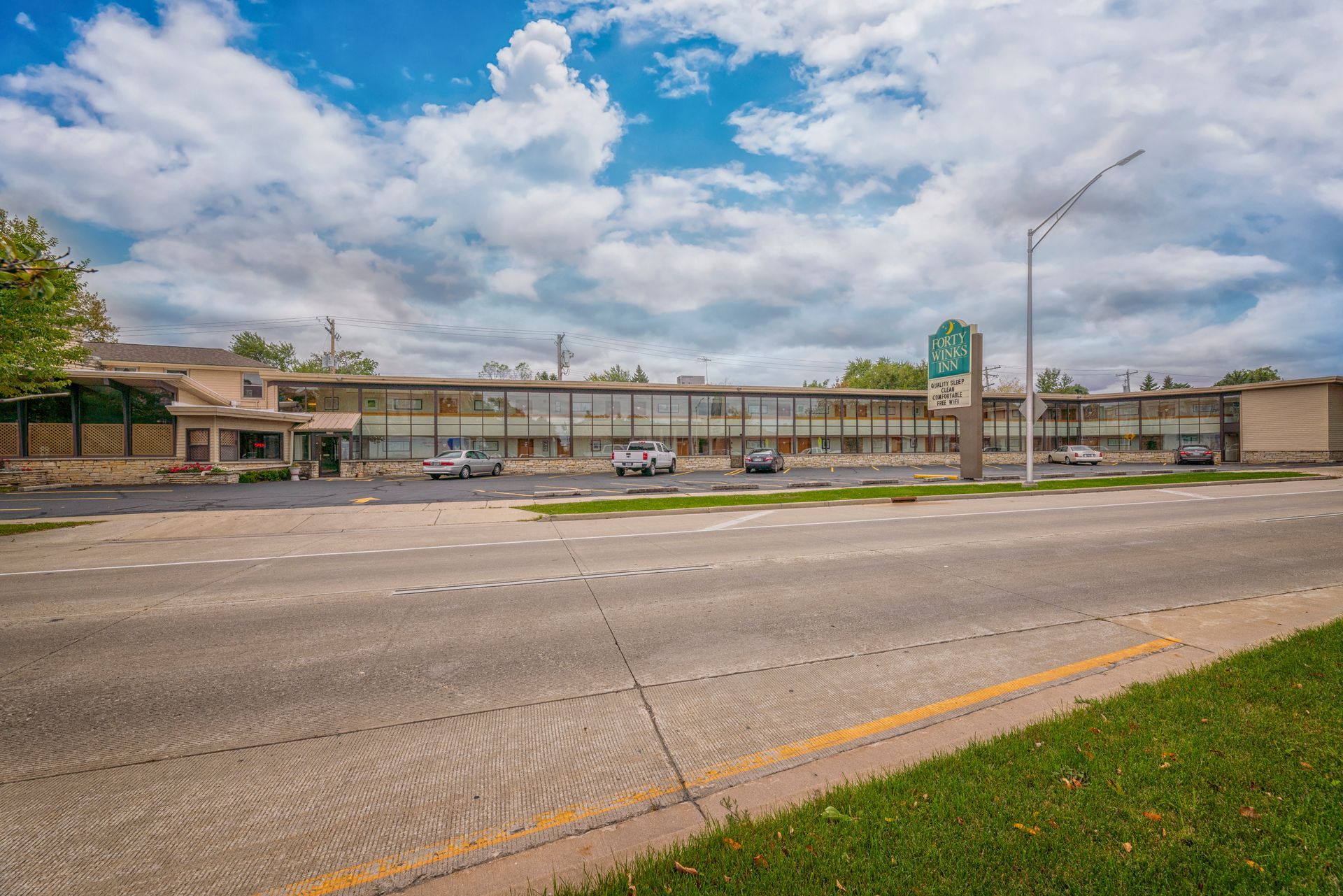 A large building with a lot of windows is sitting next to a road.