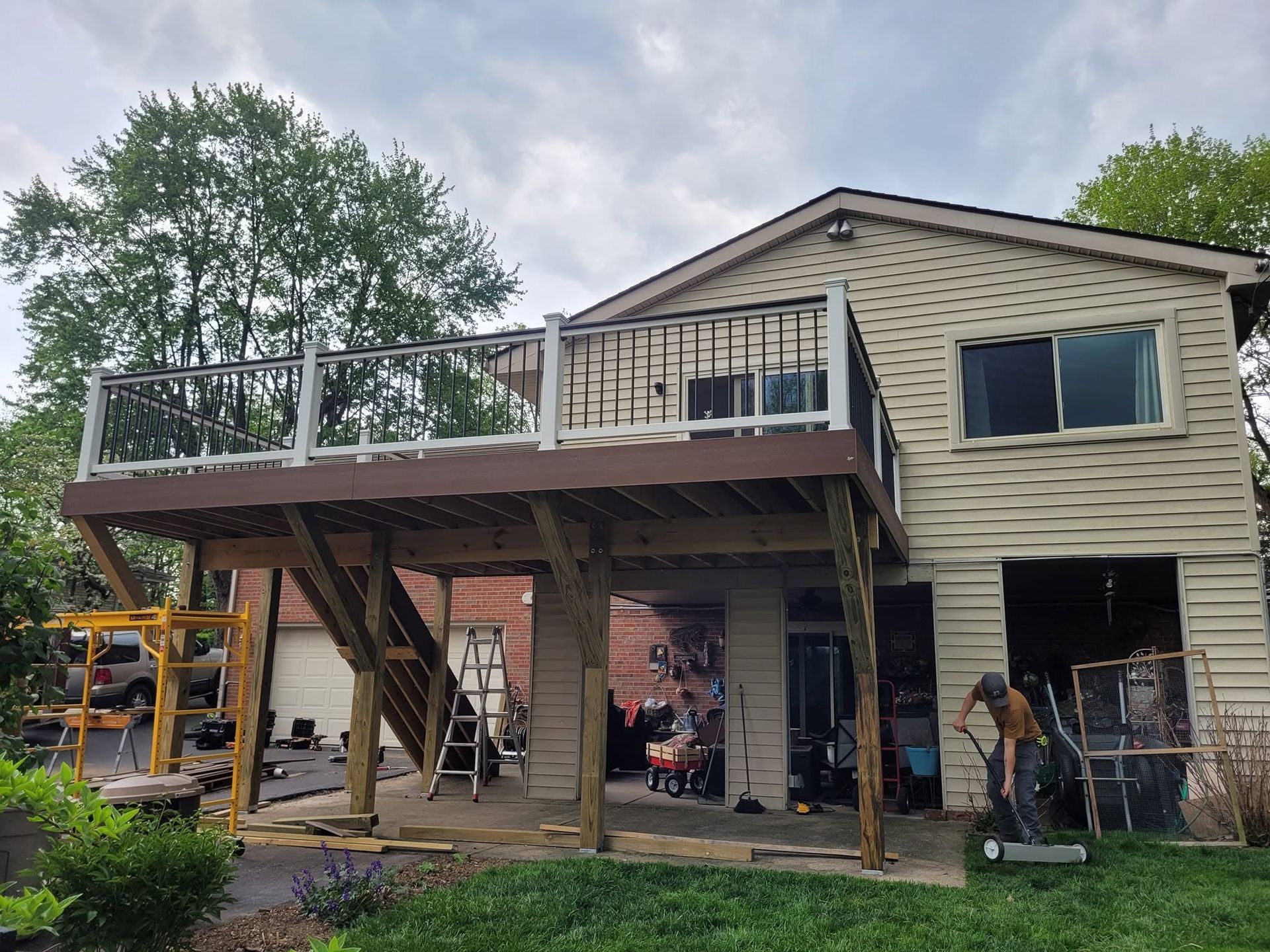 House under renovation with raised deck, exposed beams, and workers beneath the structure