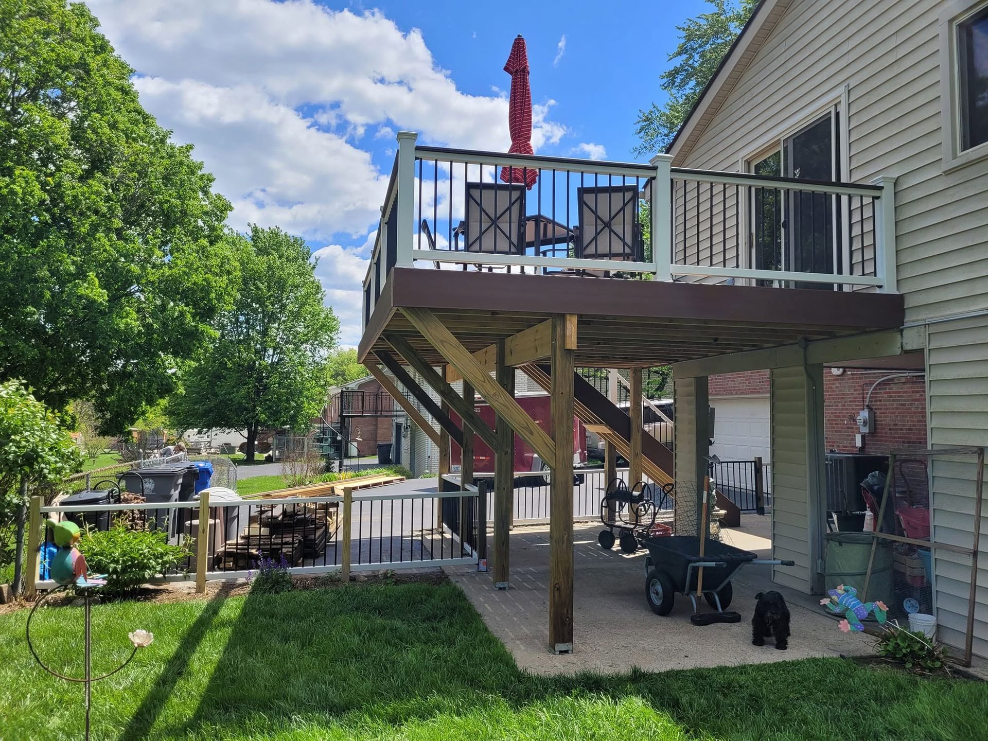 Backyard deck with stairs, patio furniture, and a lawn under a partly cloudy sky