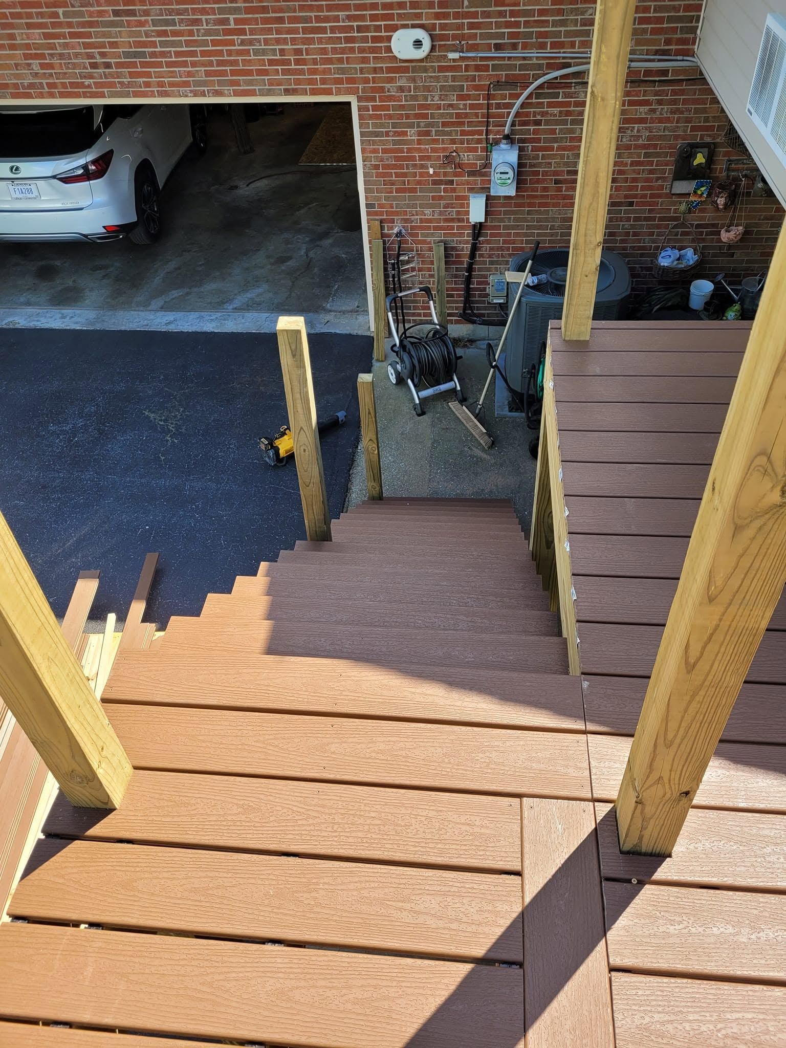 Wooden stairs with handrails leading down to a garage and driveway below.