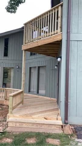Wooden accessible ramp and deck beside a gray apartment building with an upper balcony.