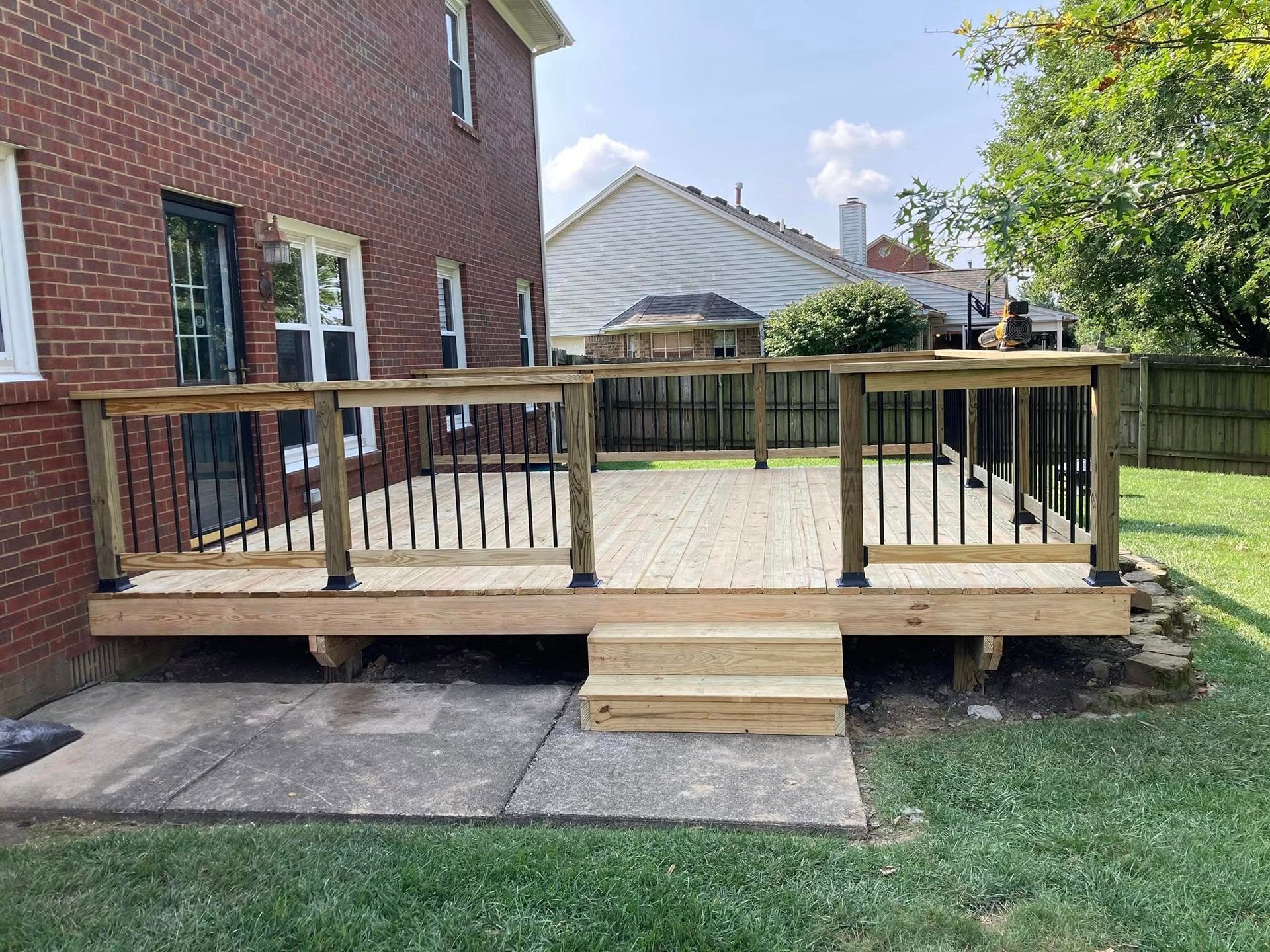 Wooden accessibility ramp with railings leading to a brick house entrance