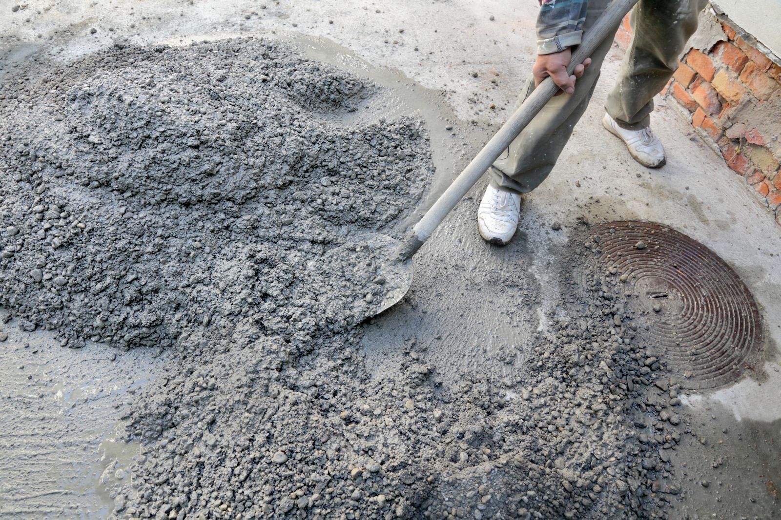 Worker shoveling wet concrete mix on a construction site