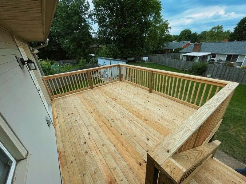 New wooden deck with railing beside a house, overlooking a yard and neighboring homes.