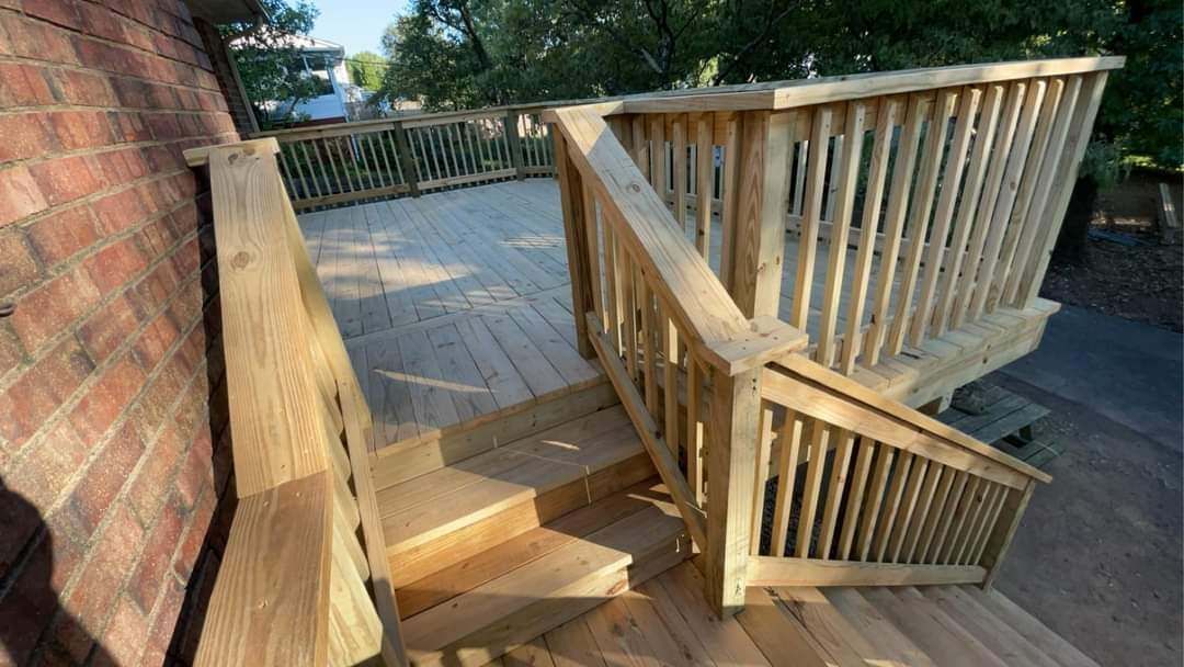 Wooden ramp and stairs with railings leading to a deck beside a brick building outdoors