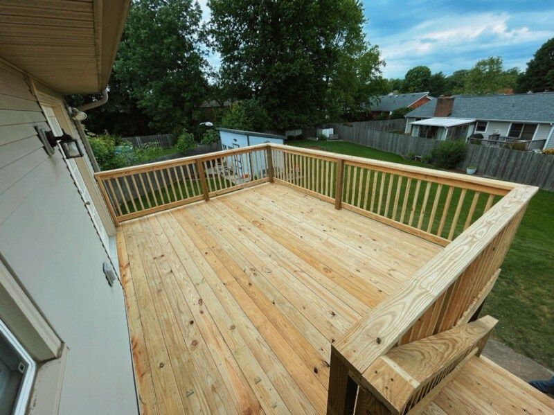 Wooden backyard deck with railings overlooking a yard and neighboring houses
