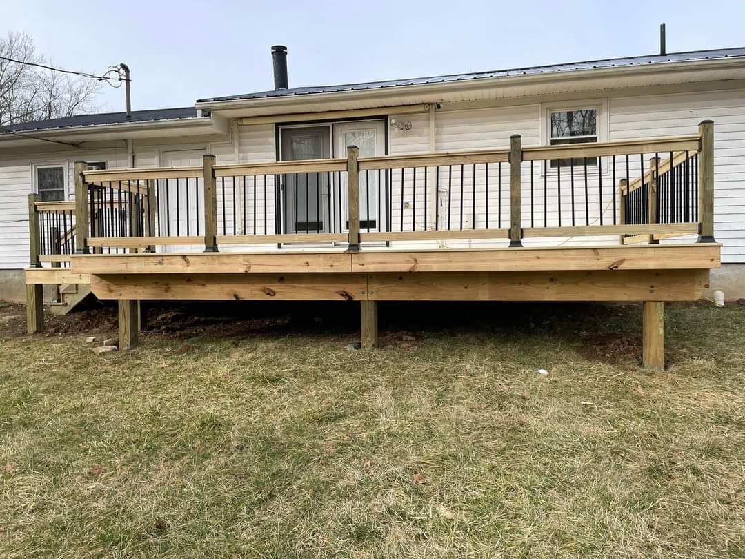 Wooden backyard deck attached to a house with railing and stairs over a grassy yard