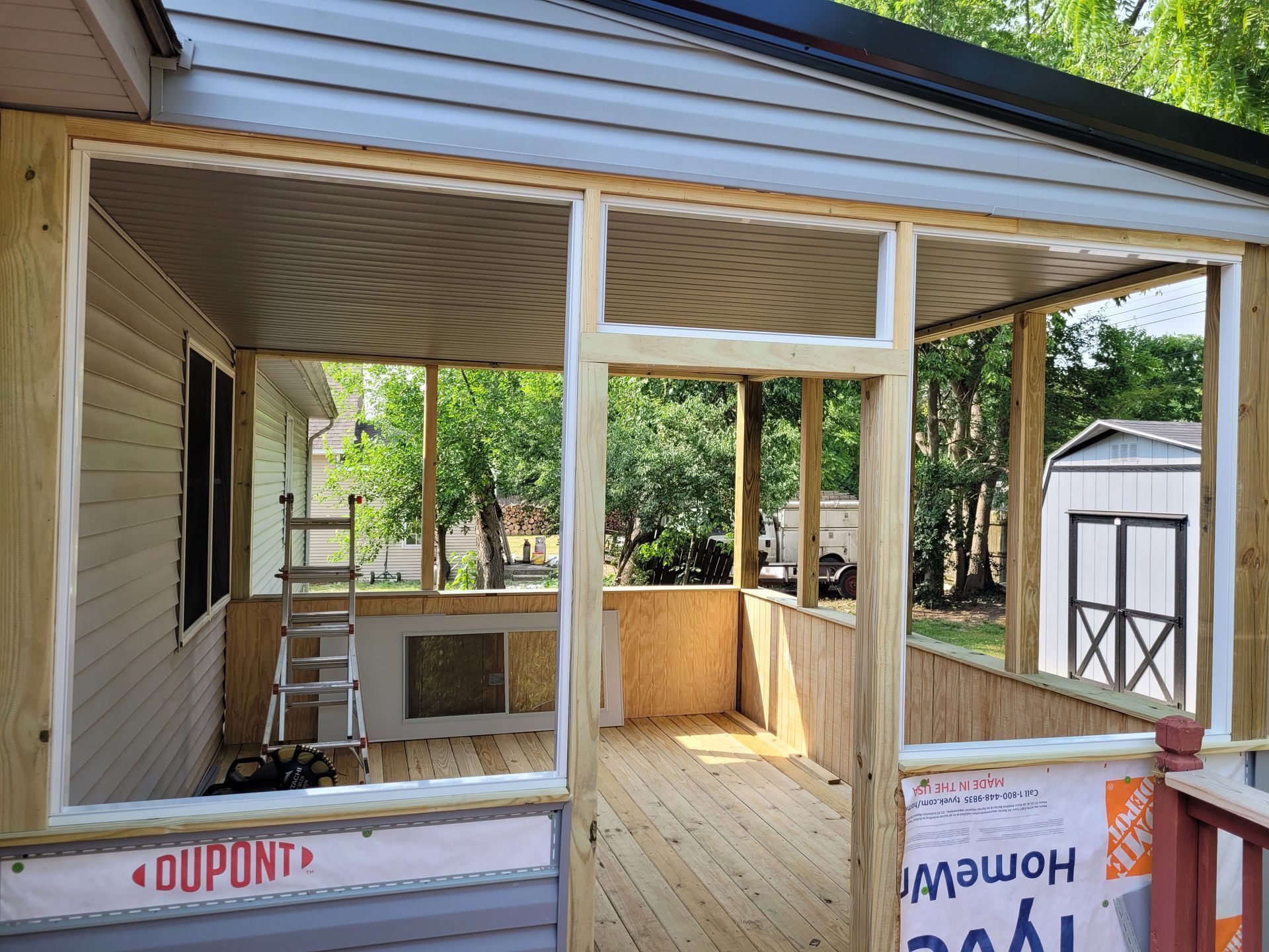 Partially built screened porch with unfinished wood framing and open windows under construction