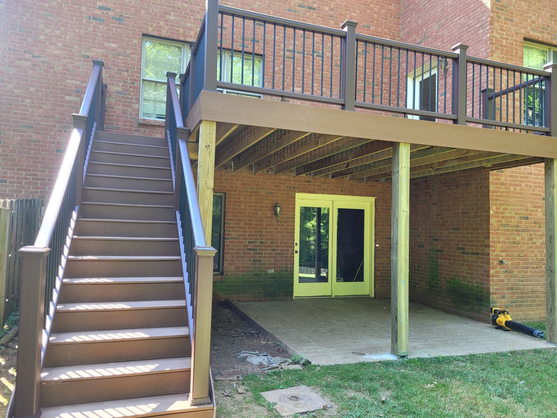 Outdoor brick building with stairs on the left and a covered patio with yellow double doors
